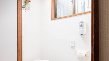 Un baño pequeño y moderno con inodoro, ventana y dispensador de gel antibacterial.
