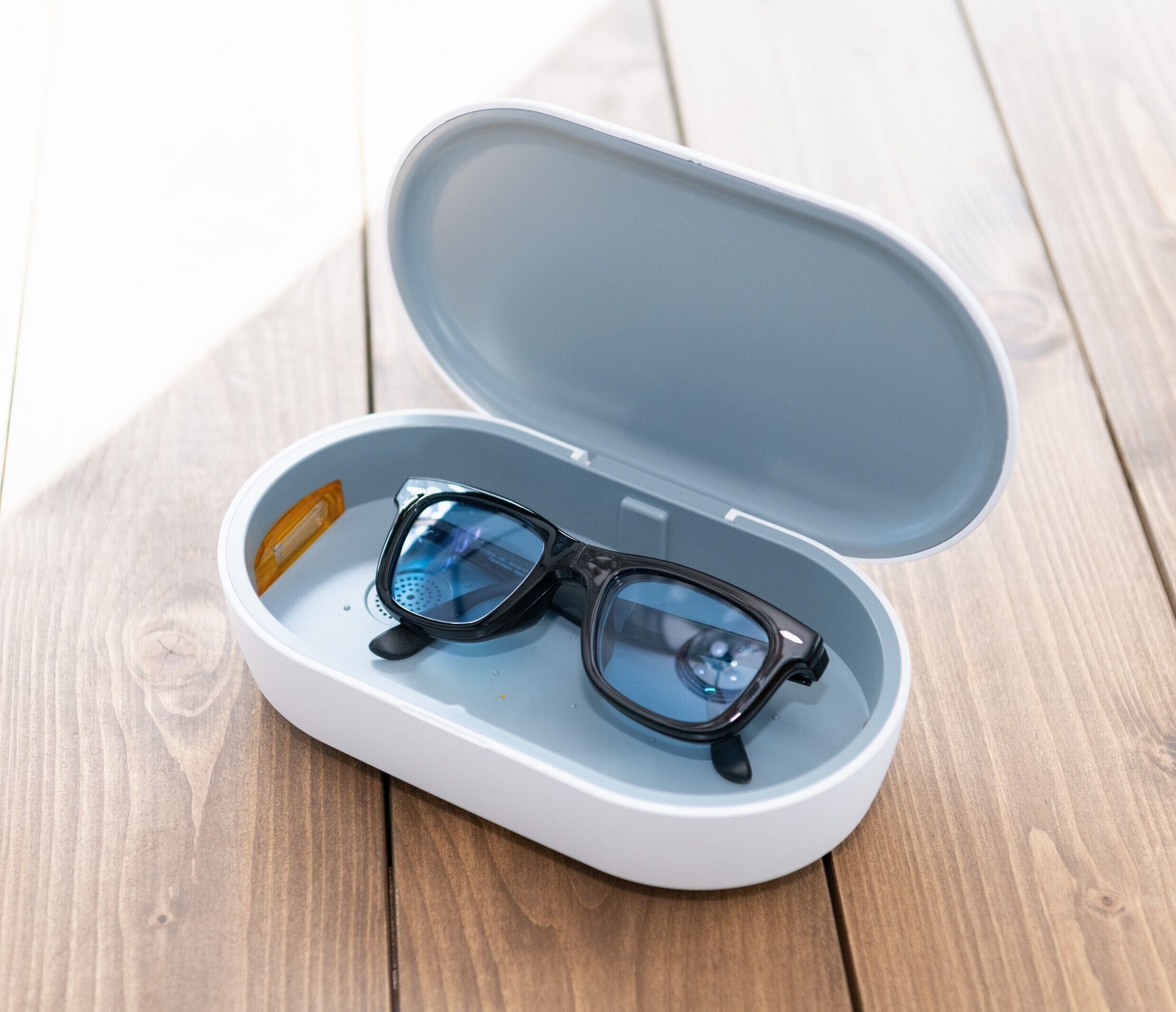 A pair of glasses in a white case with a blue interior, placed on a wooden surface.