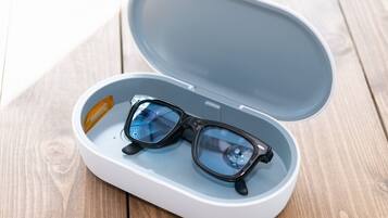 A pair of glasses in a white case with a blue interior, placed on a wooden surface.