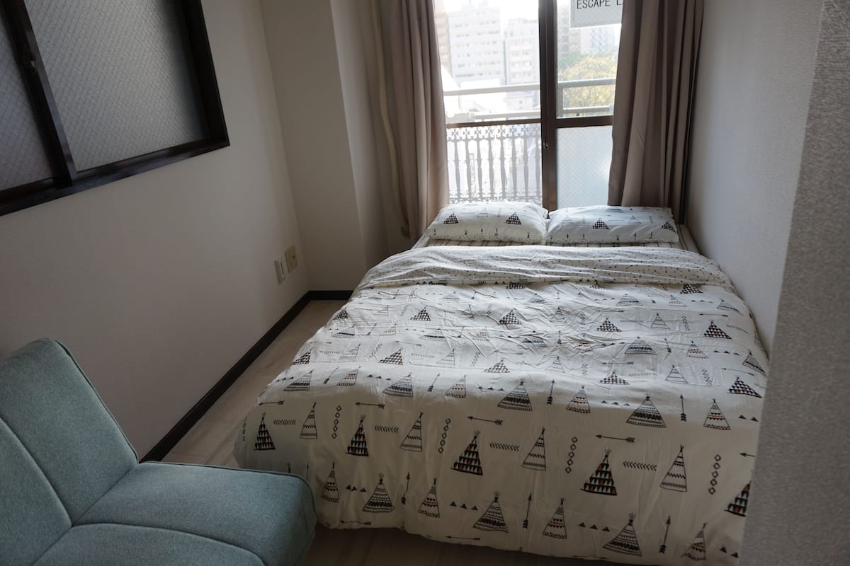 Ein Schlafzimmer mit Bett, Stuhl und einem fensterbepflanzten Fenster.