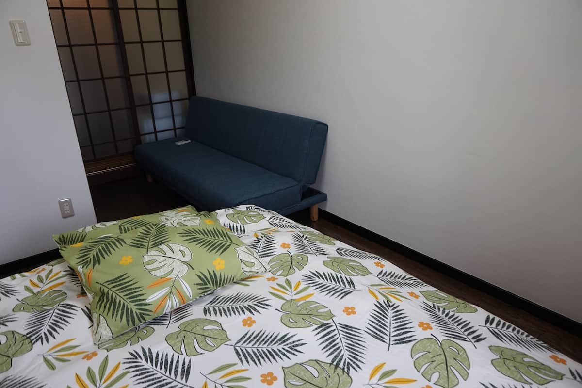 Ein Zimmer mit einem Bett, einem blauen Sofa und einer gestreiften Bettdecke.