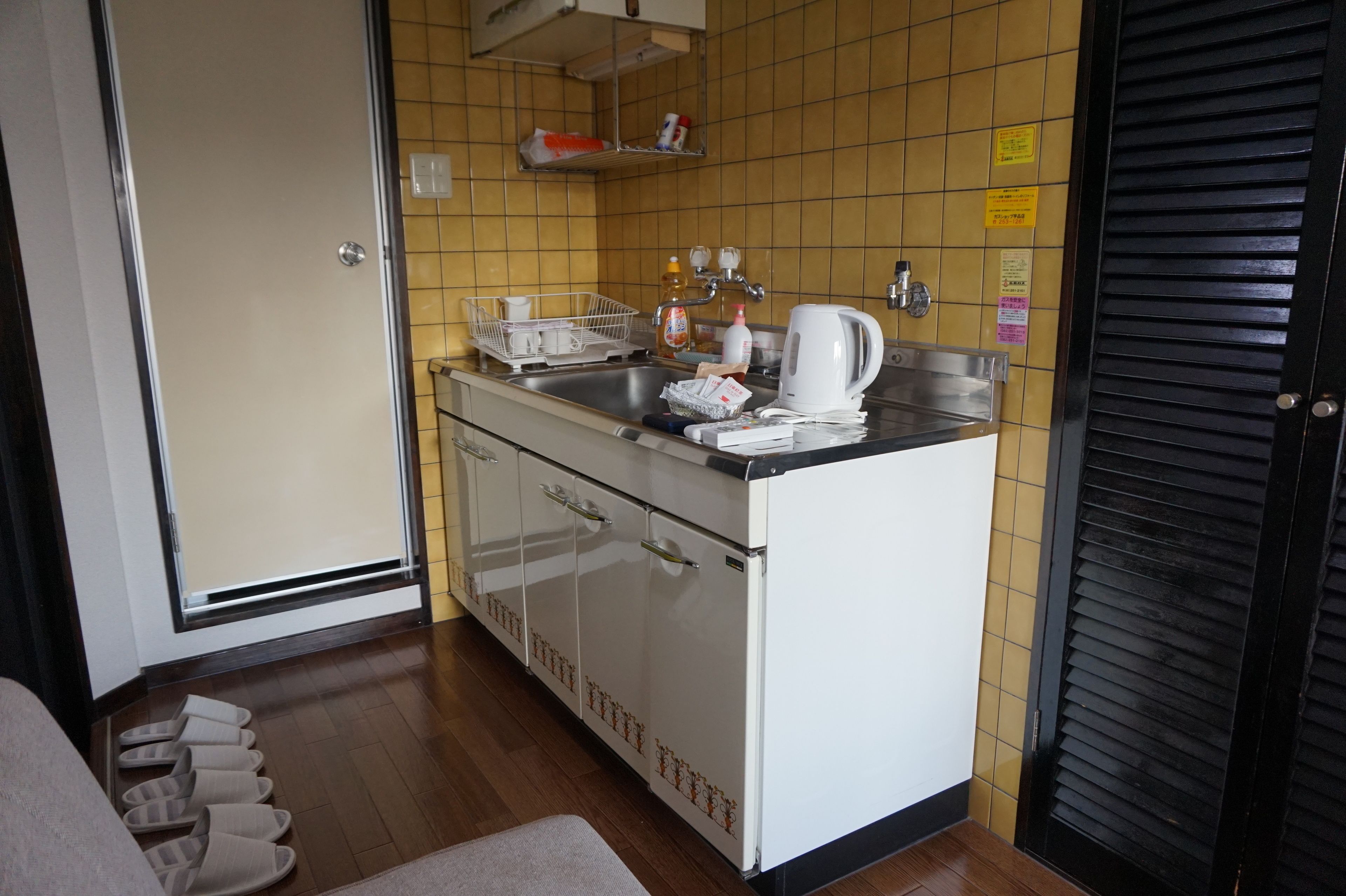A compact kitchen with a sink, white cabinets, and a tiled backsplash.