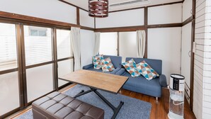 A modern living room with a sofa, a coffee table, a leather ottoman, and a water dispenser. - Blue Lagoon (Kamakura)