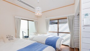 A room with two beds, a window with curtains, a ceiling light, and a thermostat on the wall. - Blue Lagoon (Kamakura)