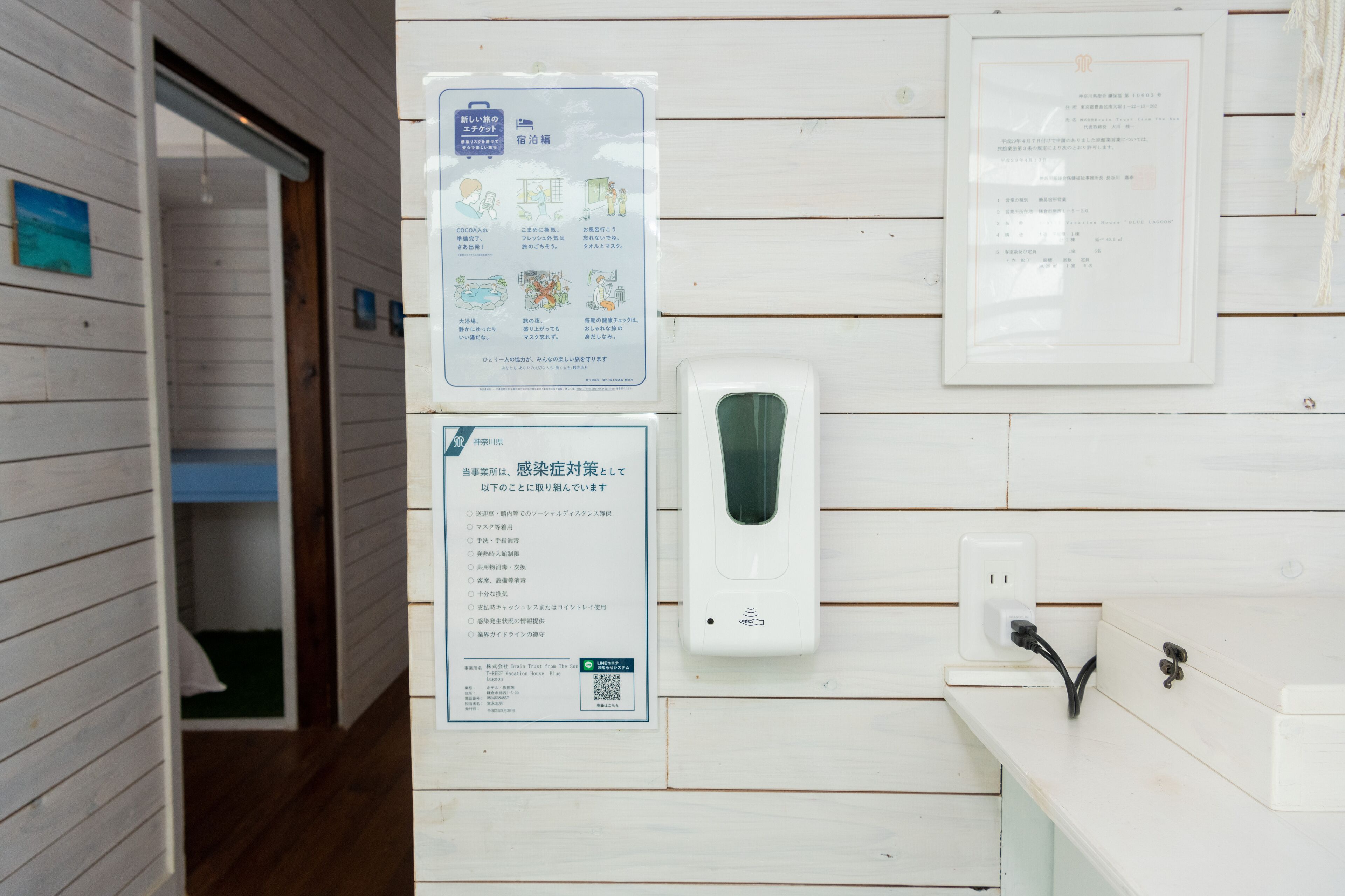 A bathroom with a hand sanitizer dispenser, a sign with health guidelines, and a wooden wall.