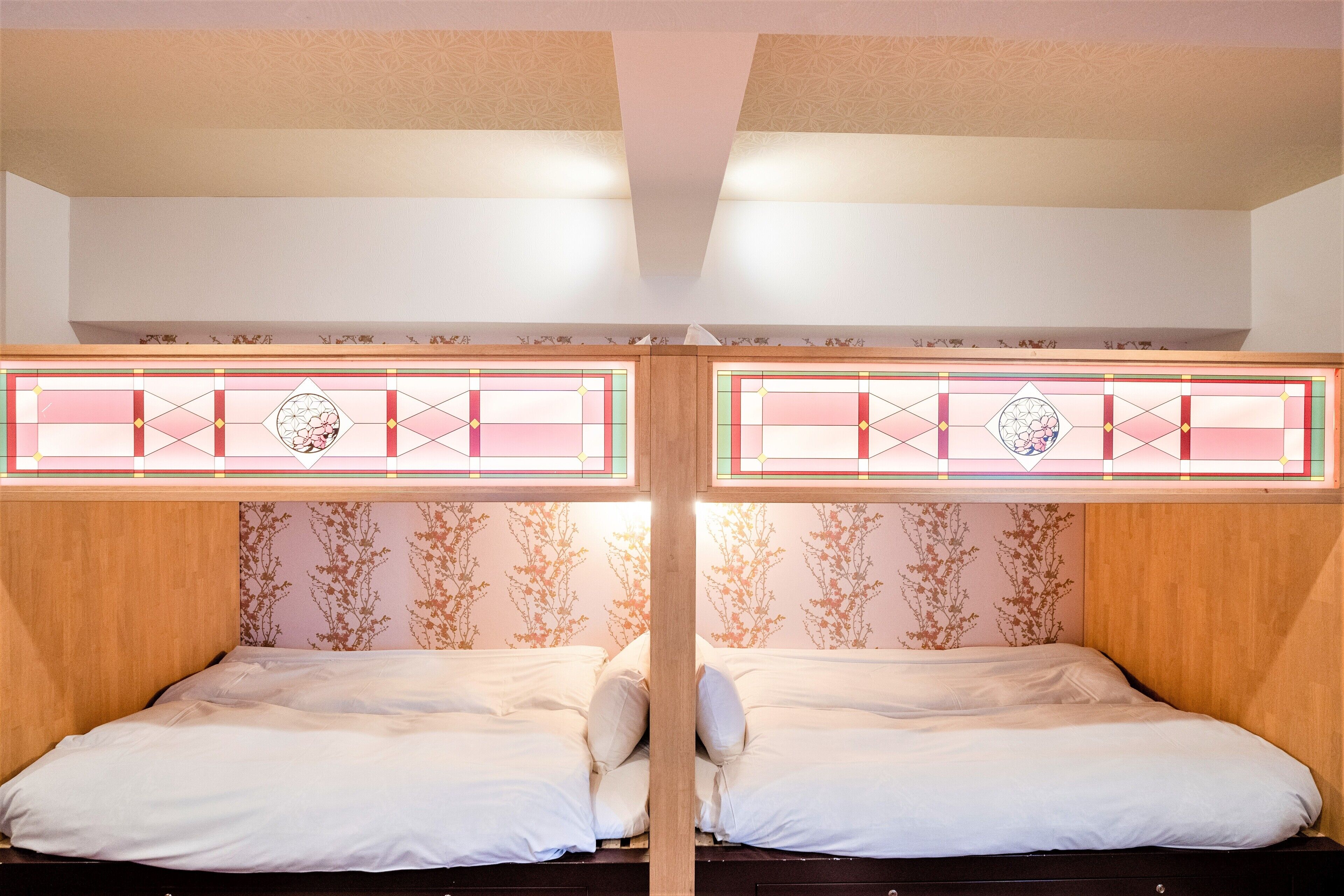 A room with two beds, wooden headboards, and floral wallpaper.