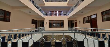 A multi-level atrium with a central open space, railings, and a grid floor.