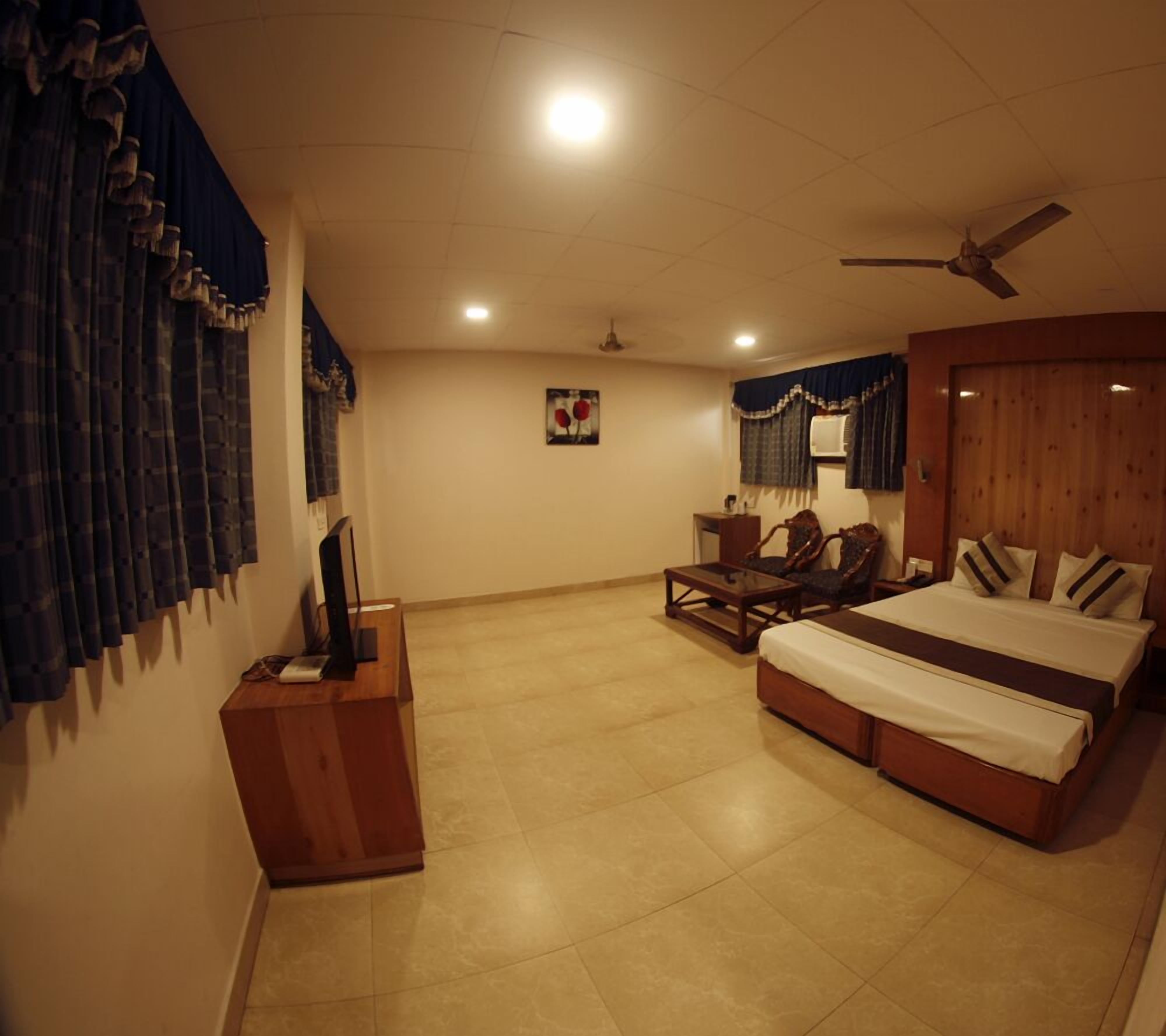 A bedroom with a bed, a desk, a chair, a ceiling fan, and a wall-mounted air conditioner.