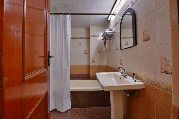 Un baño con lavamanos, espejo y cortina de ducha.