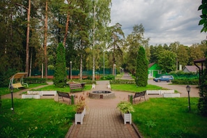 Stroll along the paved walkway to a serene central feature, surrounded by lush trees and benches for seating.