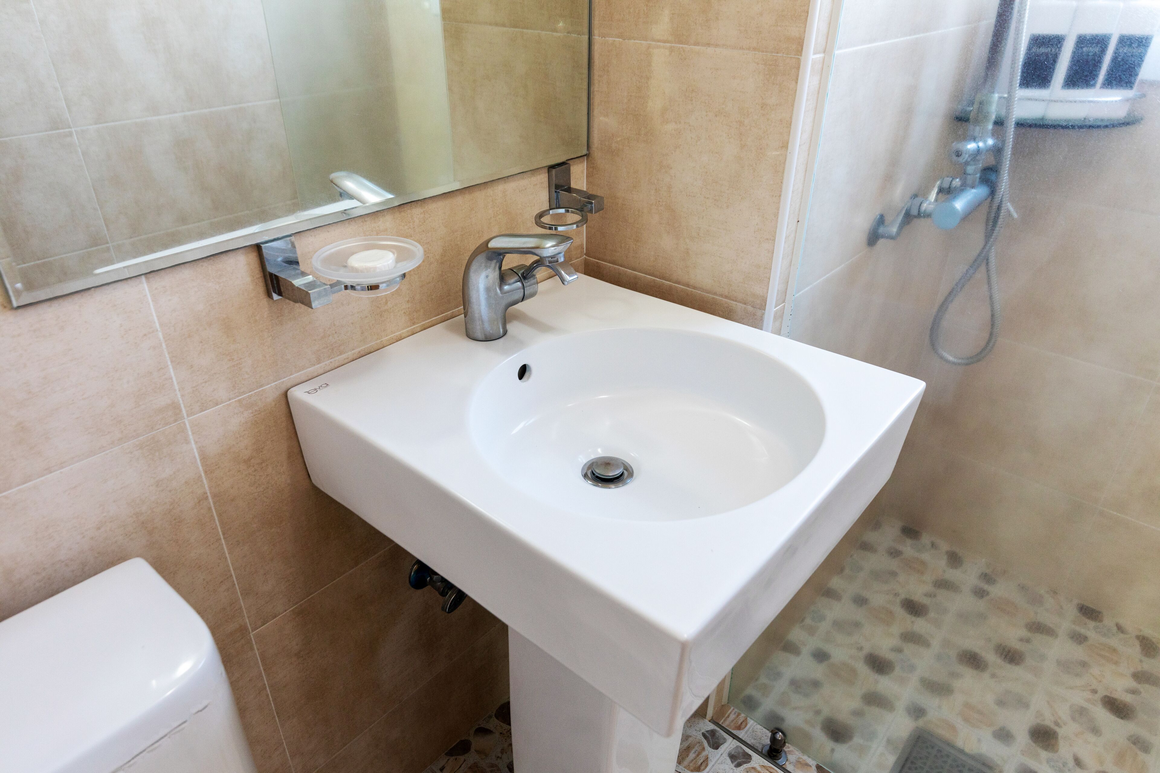 A bathroom with a white sink, a mirror, and a shower.