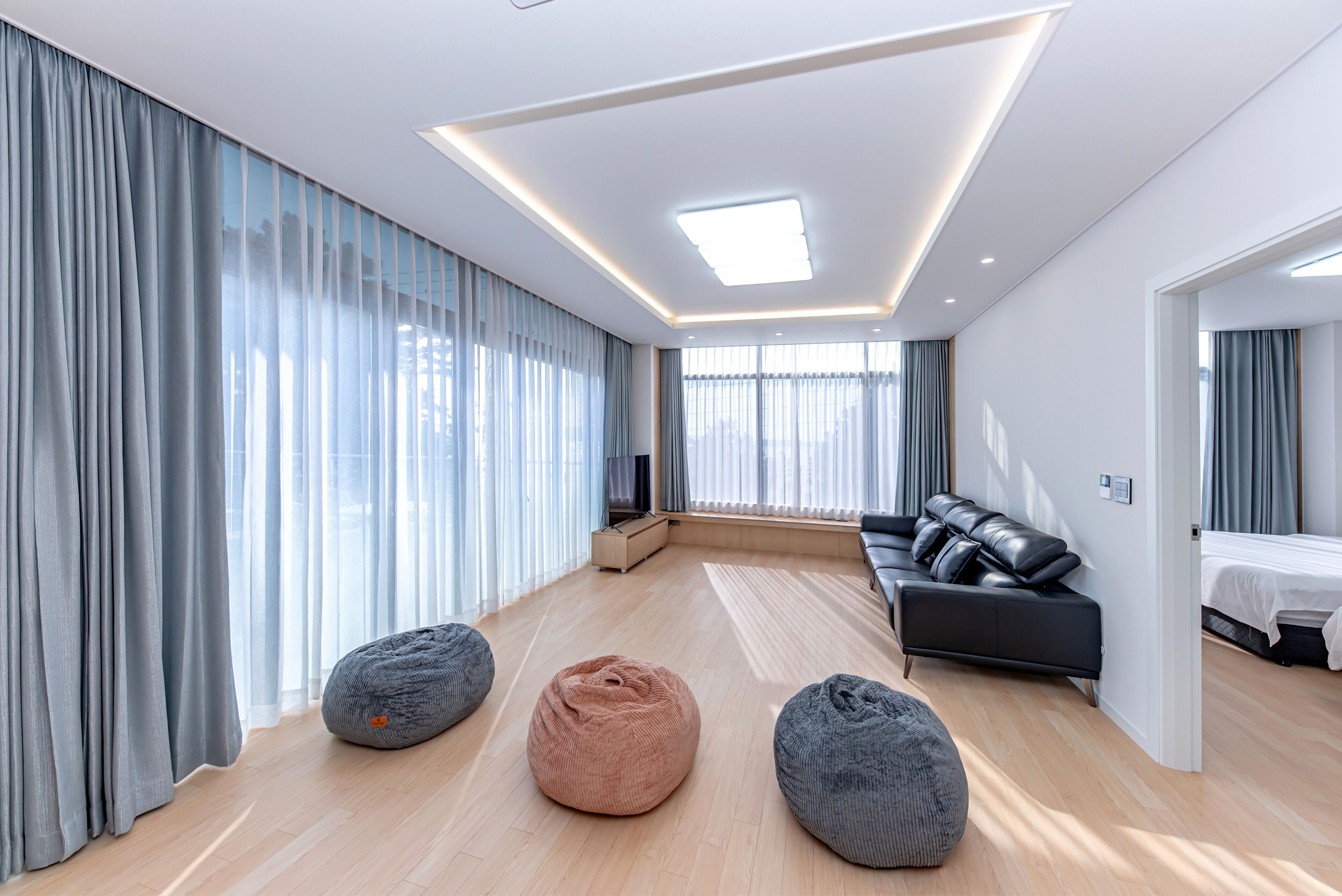 A modern living room with a sofa, bean bags, and a TV.