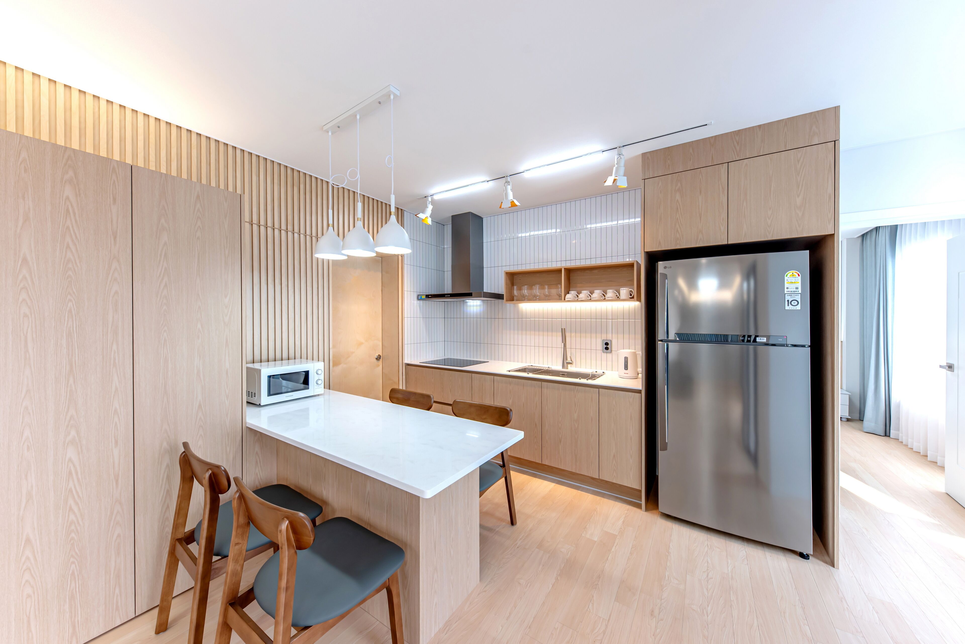 A modern kitchen with a central island, stainless steel appliances, and pendant lighting.