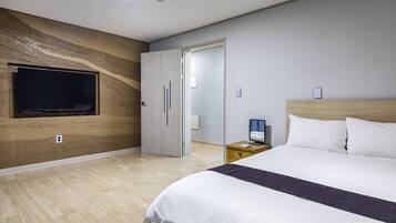 A modern hotel room with a large bed, a flat-screen TV mounted on the wall, and a wooden accent wall.