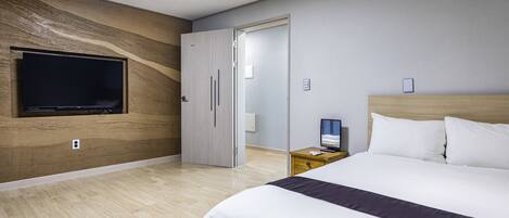 Una camera d'albergo moderna con un letto grande, una TV a schermo piatto fissata al muro e un pannello decorativo in legno.