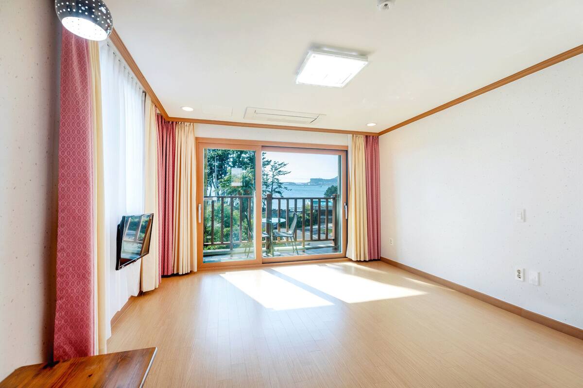 Habitación amplia con un gran ventanal corredero que da a un balcón con vistas al mar.
