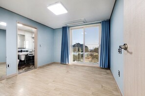 A spacious room with a large sliding glass door leading to a balcony, a built-in sink, and a light-colored wooden floor. - The Bay Jeju Resort (Seogwipo)
