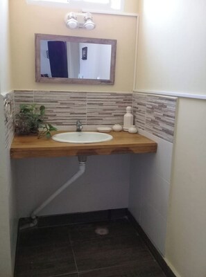 A bathroom with a wooden vanity, a white sink, a mirror, and a tiled backsplash. - Colonial Belgrano (San Salvador de Jujuy)
