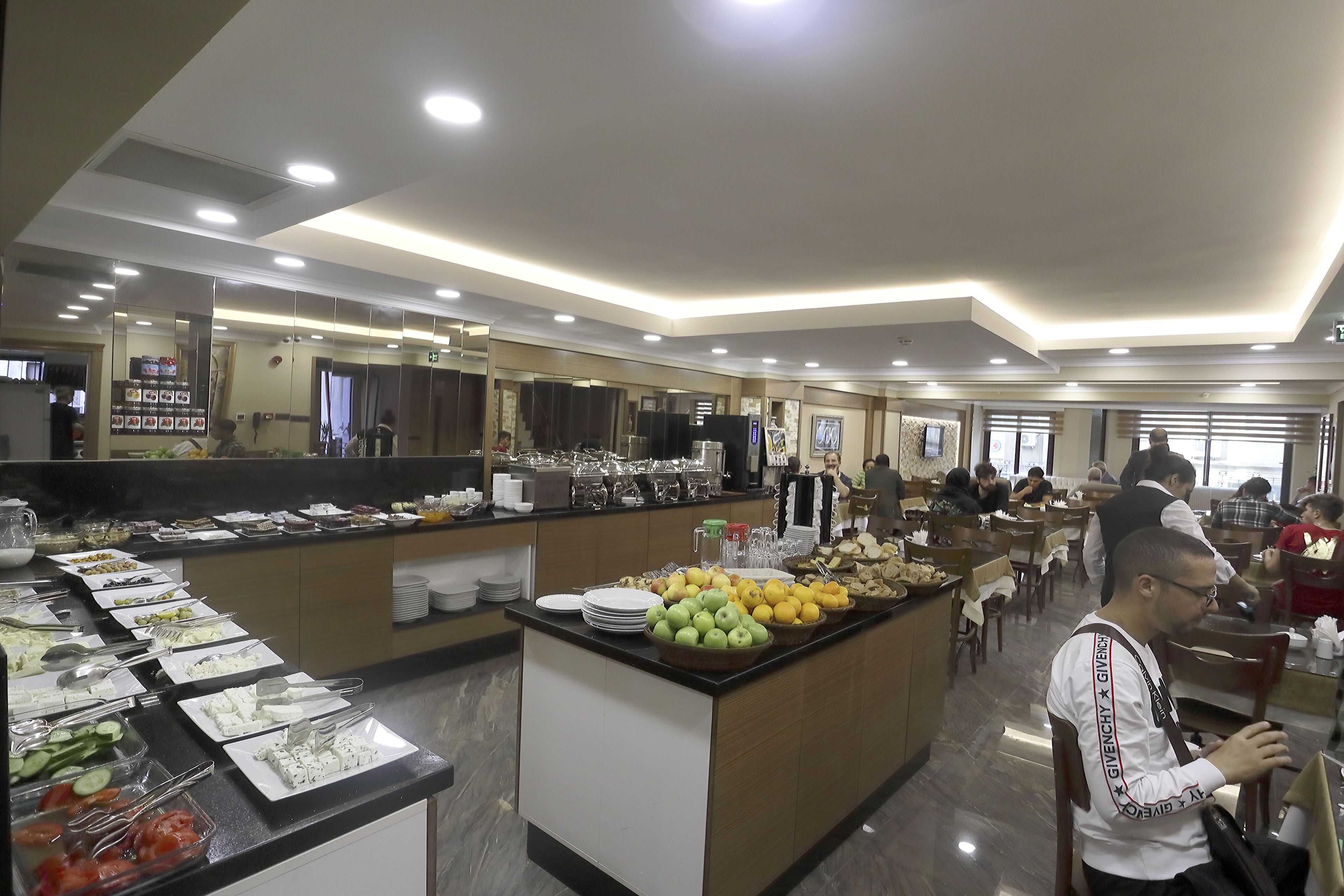 A buffet area with various food items and a man sitting at a table.