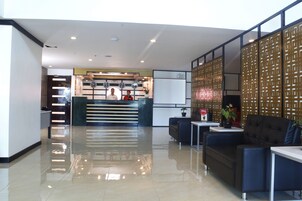Un moderno vestíbulo de hotel con mostrador de recepción, zona de estar y paneles decorativos.