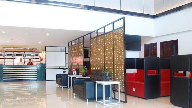 A modern lobby with a reception desk, seating area, and a decorative partition. - Hotel Sogo Alabang South Road (Muntinlupa)