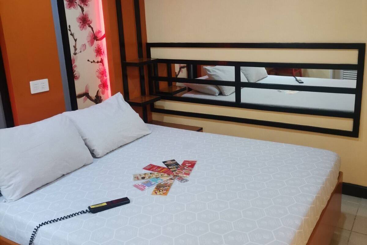 Een hotelkamer met een bed, een wandairconditioner en een decoratief bloemenpaneel.