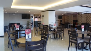 A modern restaurant with multiple dining tables and chairs, a flat-screen TV mounted on the wall, and a decorative partition with intricate patterns. - Hotel Sogo Alabang South Road (Muntinlupa)