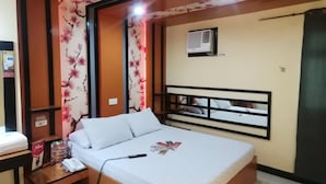 A bedroom with a bed, bedside table, and a wall-mounted air conditioner. - Hotel Sogo Alabang South Road (Muntinlupa)