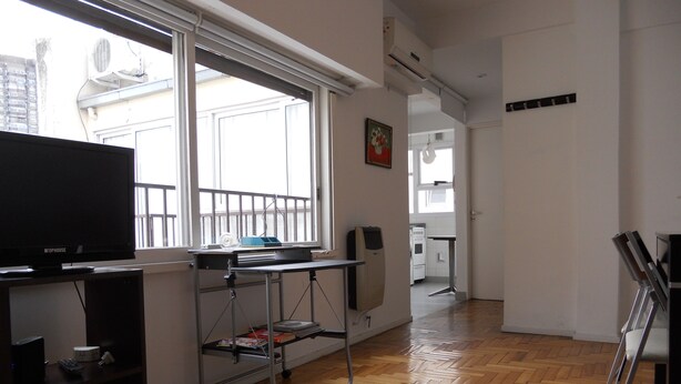 A modern kitchen with a built-in oven and microwave, a dining area with a table and chairs, and a large window providing natural light. - Santa Fe & Carranza By Foreign In Baires (Buenos Aires)
