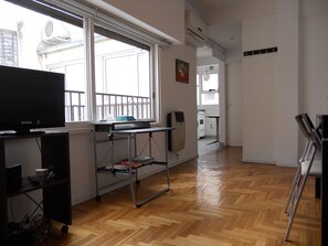 A modern kitchen with a built-in oven and microwave, a dining area with a table and chairs, and a large window providing natural light. - Santa Fe & Carranza By Foreign In Baires (Buenos Aires)