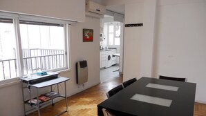 A room with a dining table, chairs, a window with a view, a radiator, and a washing machine in the background. - Santa Fe & Carranza By Foreign In Baires (Buenos Aires)