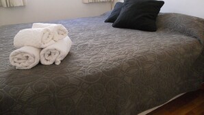 A neatly made bed with a grey quilt and rolled white towels. - Santa Fe & Carranza By Foreign In Baires (Buenos Aires)