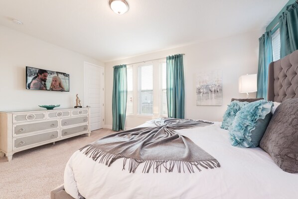 A bedroom with a bed, a dresser, a television, and a window with curtains. - Groovy Mouse House with private pool and spa near Disney (Kissimmee)