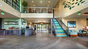 Eine großzügige Lobby mit einer zentralen Treppe, einem Empfangstresen und einer Wand mit Fischornamenten.