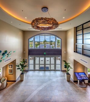 A hotel lobby with a modern chandelier, a large arched entrance, and potted plants. - Groovy Mouse House with private pool and spa near Disney (Kissimmee)