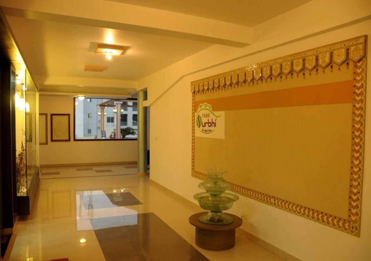 A hotel lobby with a reception desk, a decorative wall with a sign, and a glass water feature.