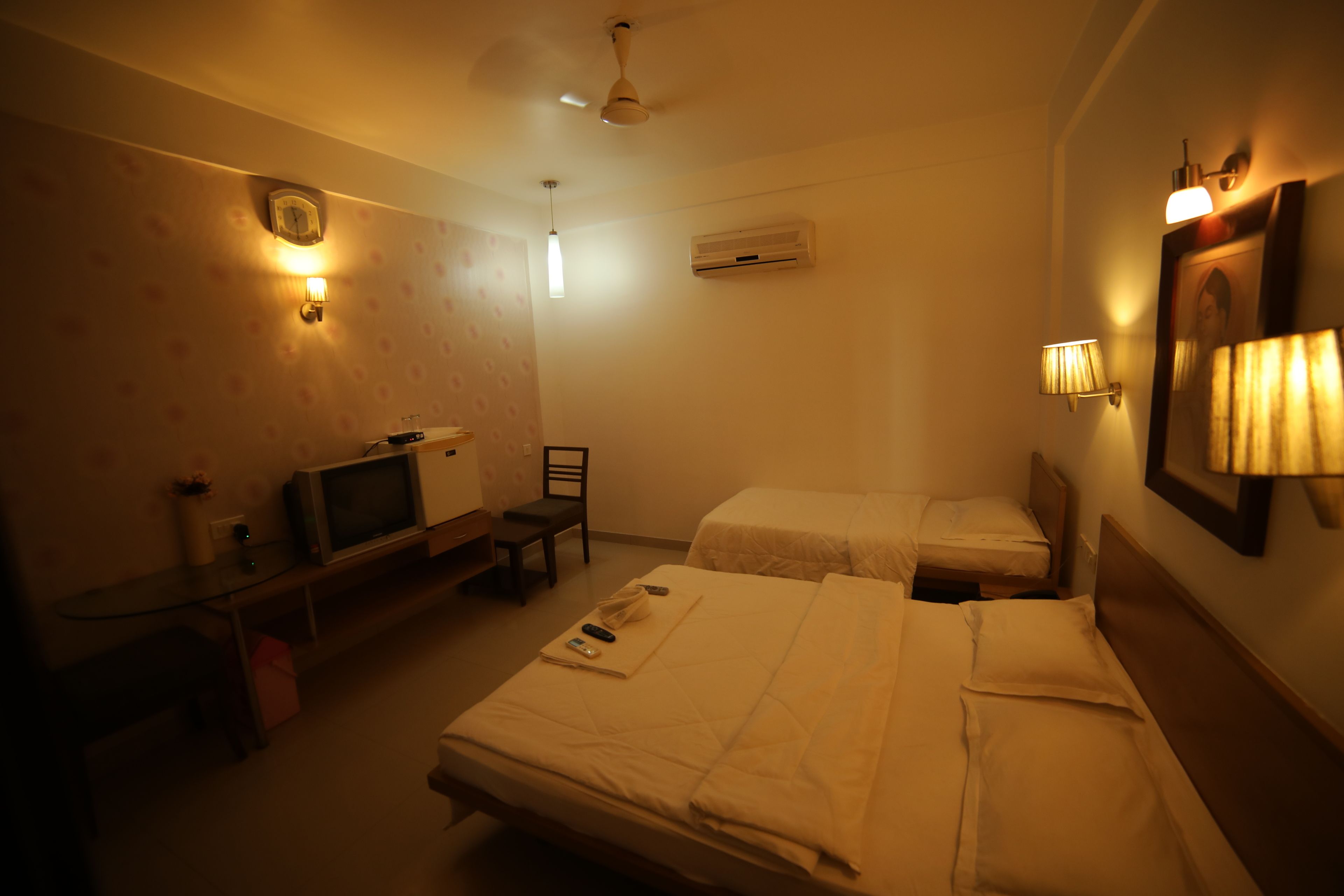 A hotel room with two beds, a television, a desk, and a chair.