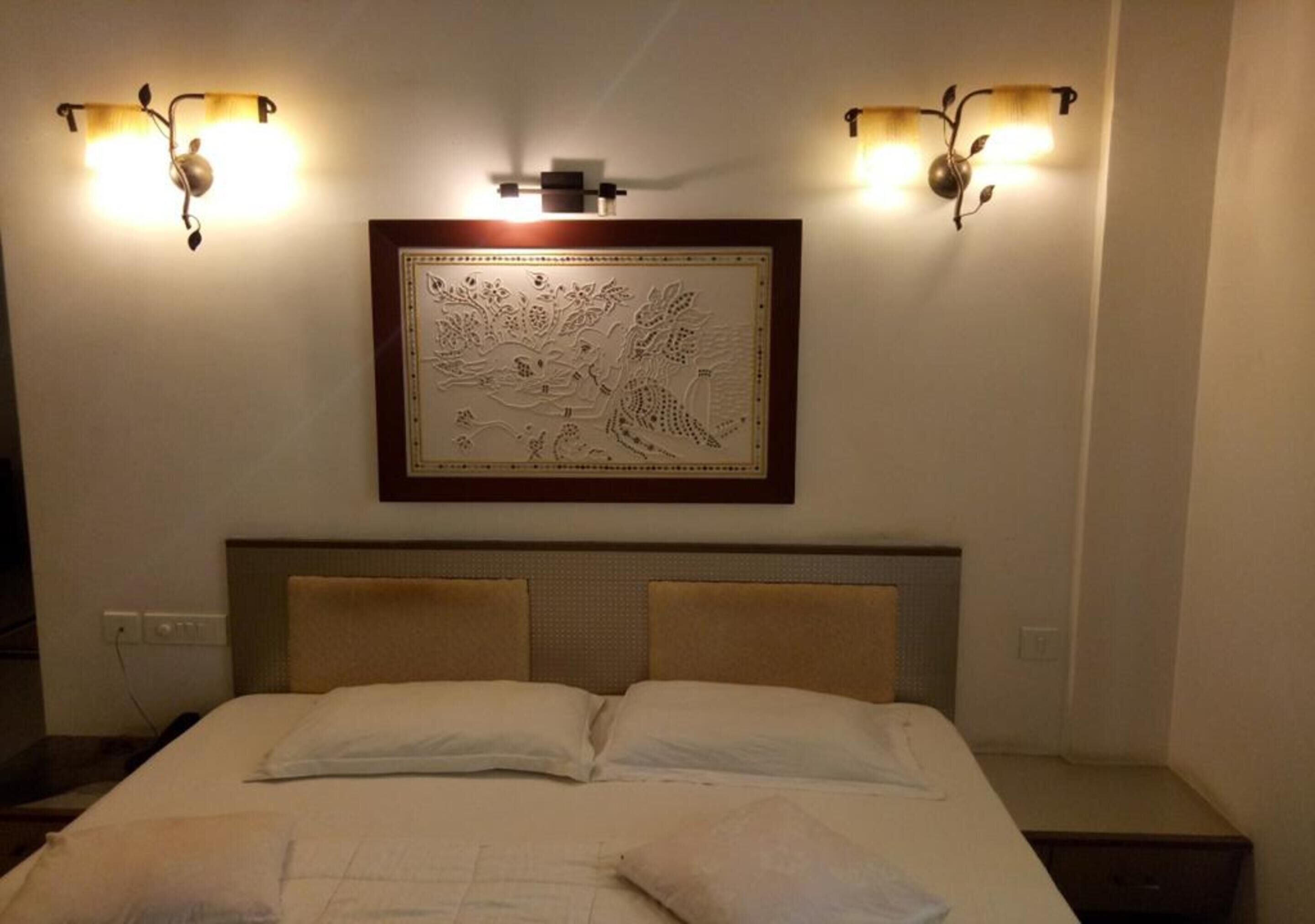 Ein Hotelzimmer mit einem Bett, zwei Wandleuchten und einem gerahmten Kunstwerk darüber.