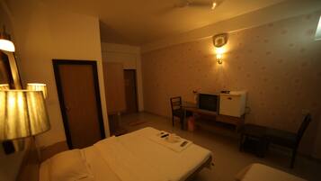 A hotel room with a bed, a desk with a computer, a chair, and a TV.