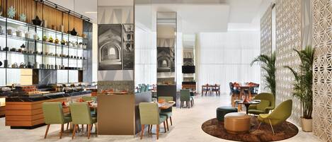 A modern hotel lobby with a central bar area, seating arrangements, and decorative elements.