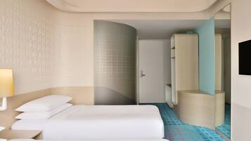 A hotel room with a bed, a nightstand, a lamp, a wardrobe, and a mirror.