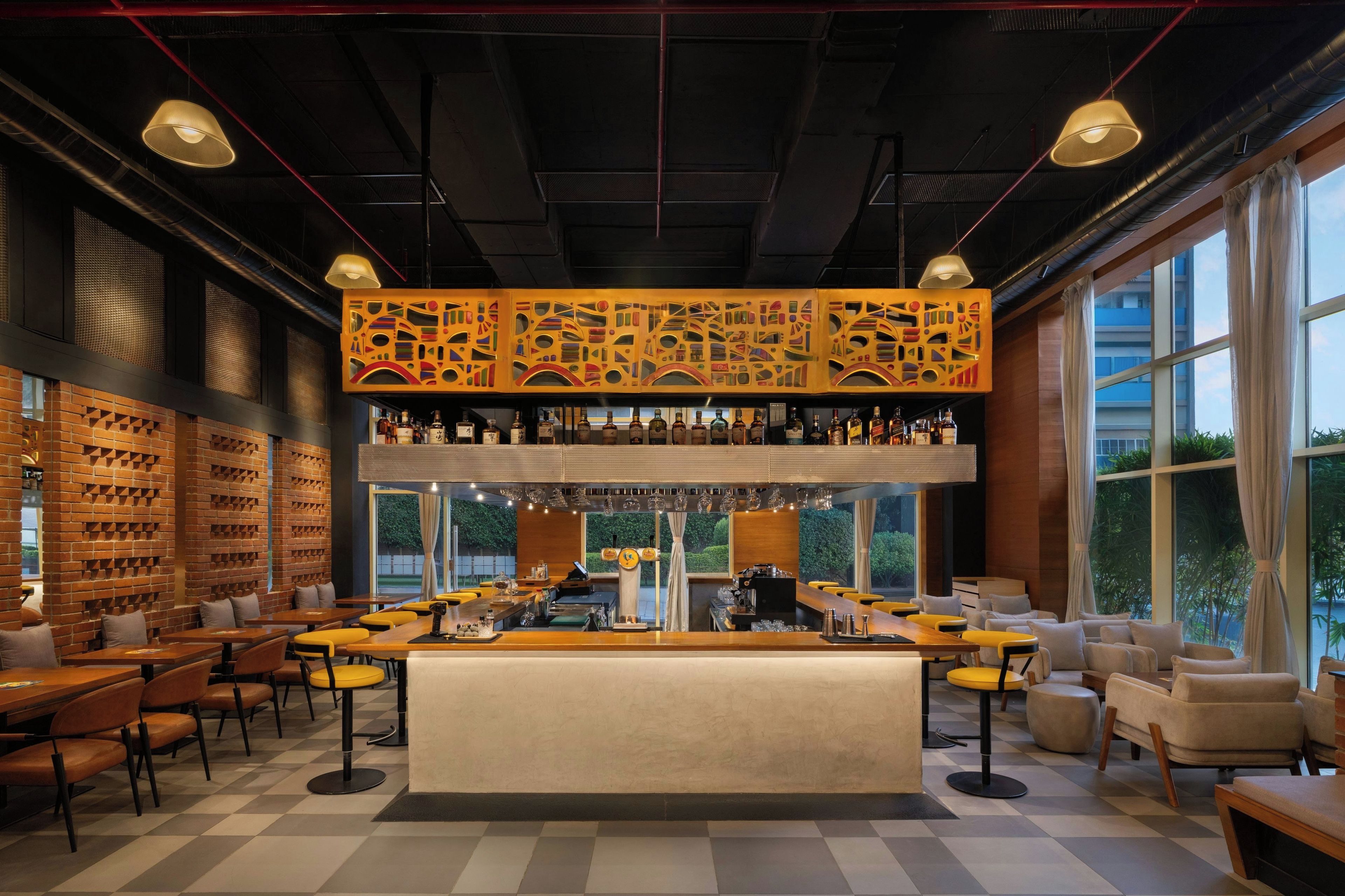 A bar area with a counter, stools, and a variety of bottles.