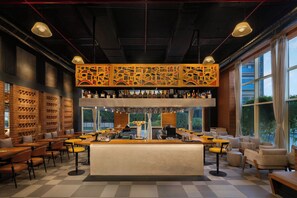 A bar area with a counter, stools, and a variety of bottles. - Fairfield by Marriott Hyderabad Gachibowli (Hyderabad)