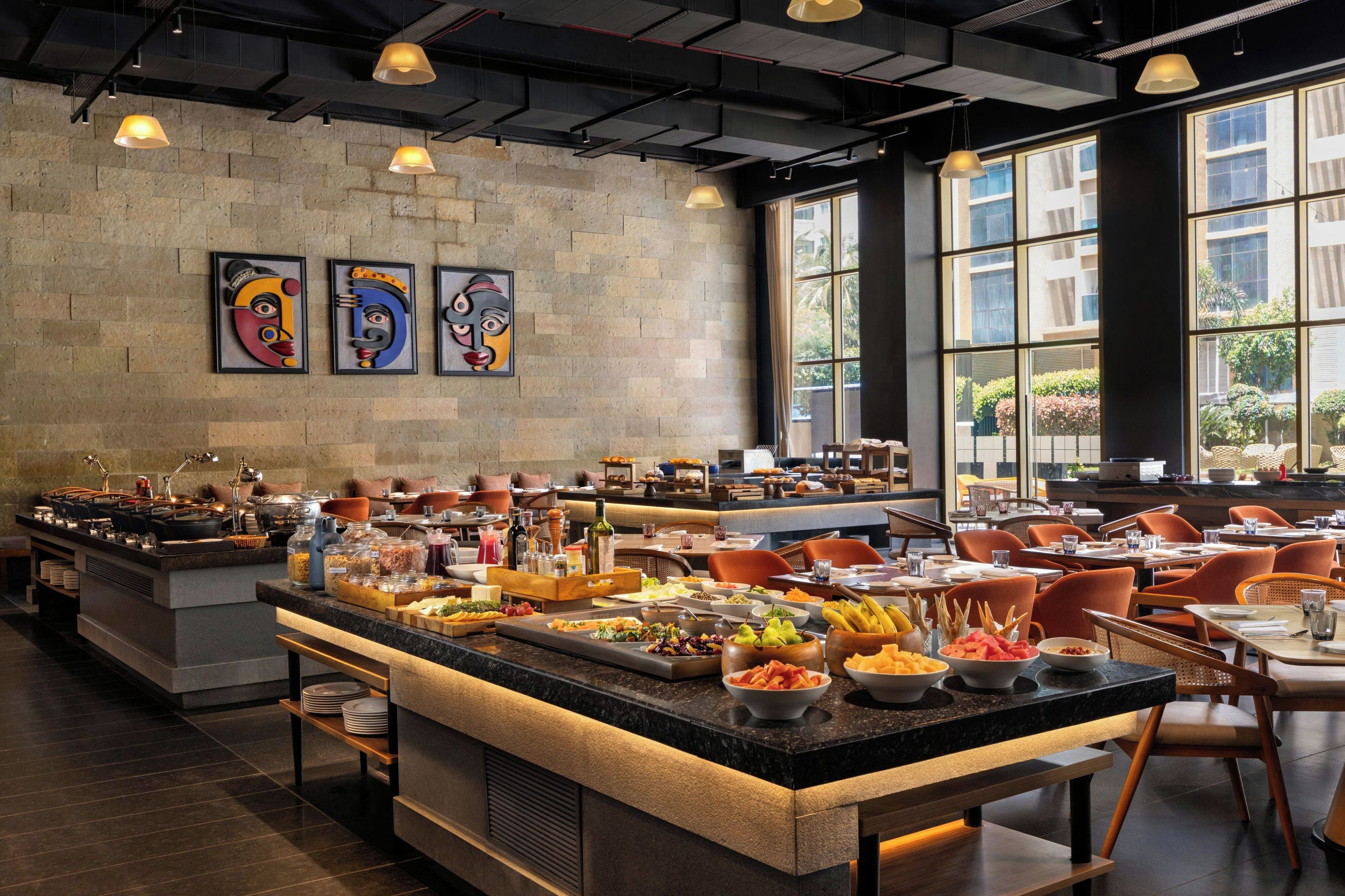 Un restaurante con barra de buffet, una pared de piedra y obras de arte.