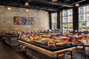 A restaurant with a buffet setup, a stone wall, and artwork. - Fairfield by Marriott Hyderabad Gachibowli (Hyderabad)
