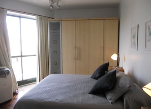 A bedroom with a bed, pillows, a nightstand, a lamp, a wardrobe, and a sliding glass door. - Santa Fe & Humboldt By Foreign In Baires (Buenos Aires)
