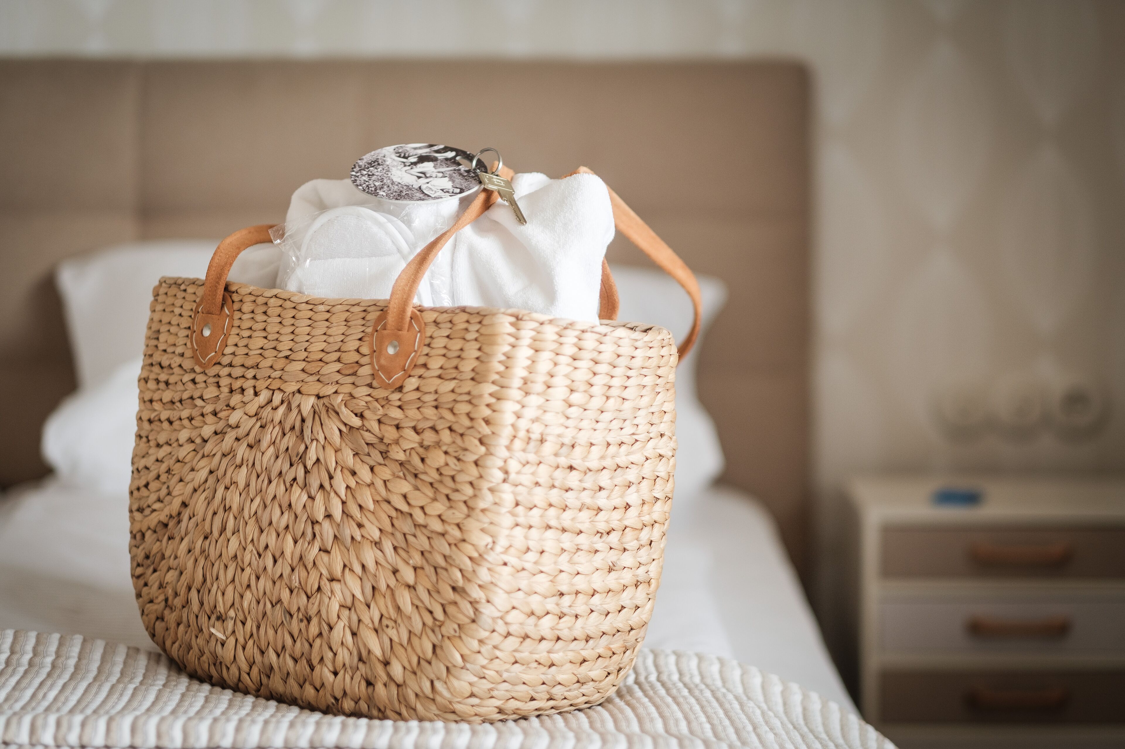 A woven basket with handles on a bed.