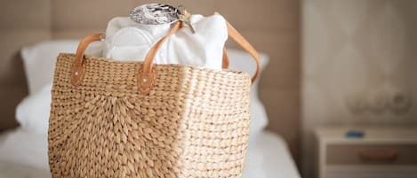 A woven basket with handles on a bed.