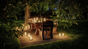 An outdoor dining area with a wooden table and chairs, surrounded by candles and greenery. - Hotel Sonnenhof (Neuweiler)