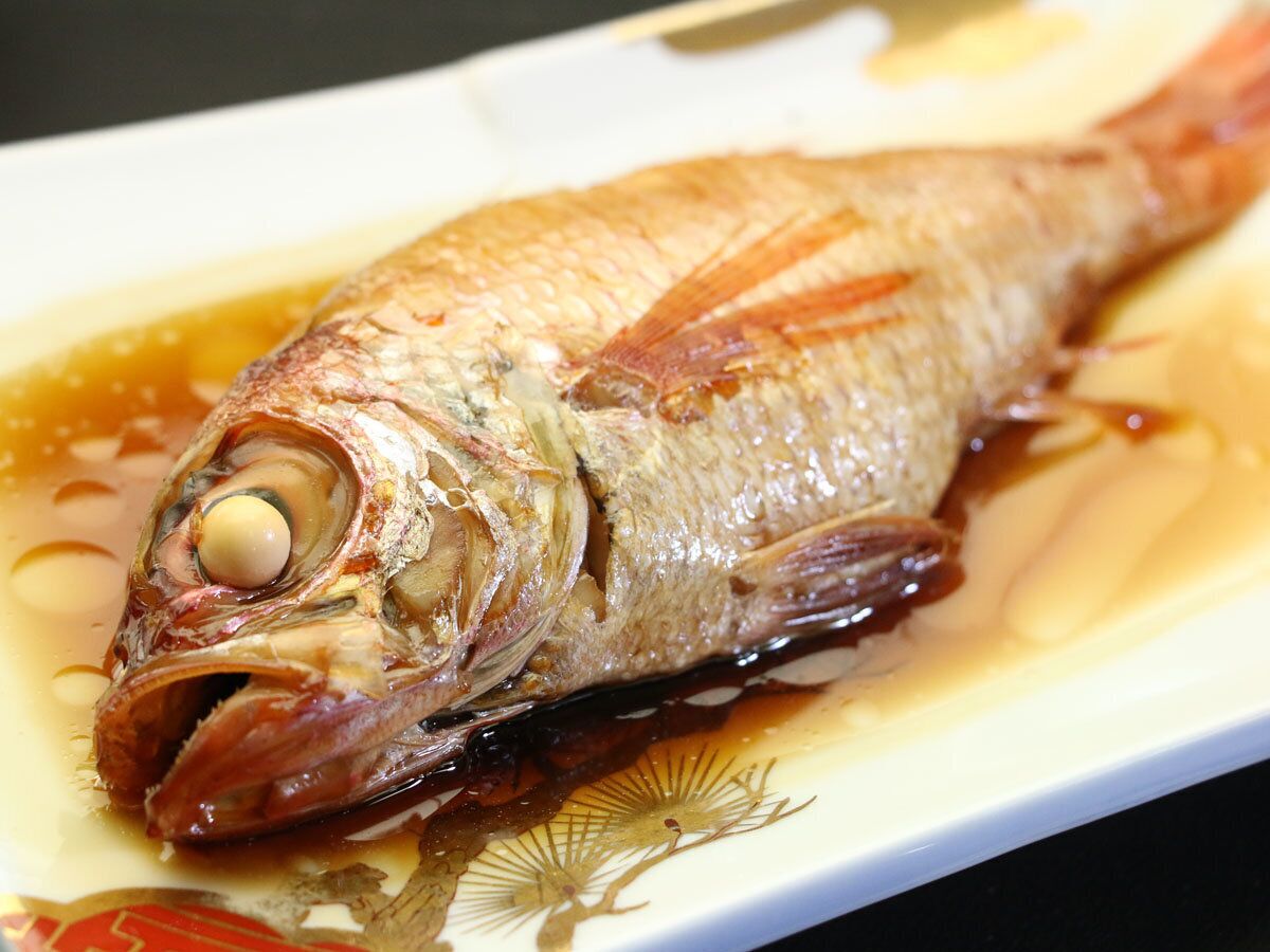 Ein ganzer Fisch auf einem Teller mit Soße.